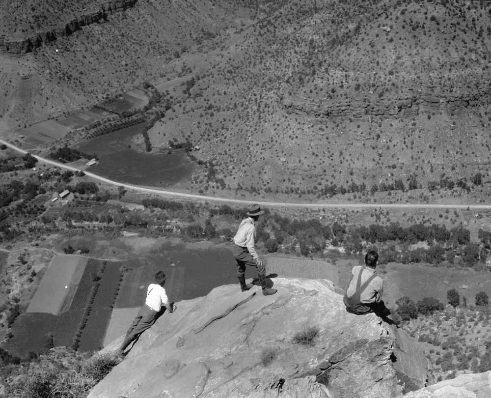 Eivind Scoyen, first superintendent of Zion National Park, Angus Woodbury, first ranger naturalist of Zion National Park, and Schieffer look down into valley from edge of rock on a Bridge Mountain hike